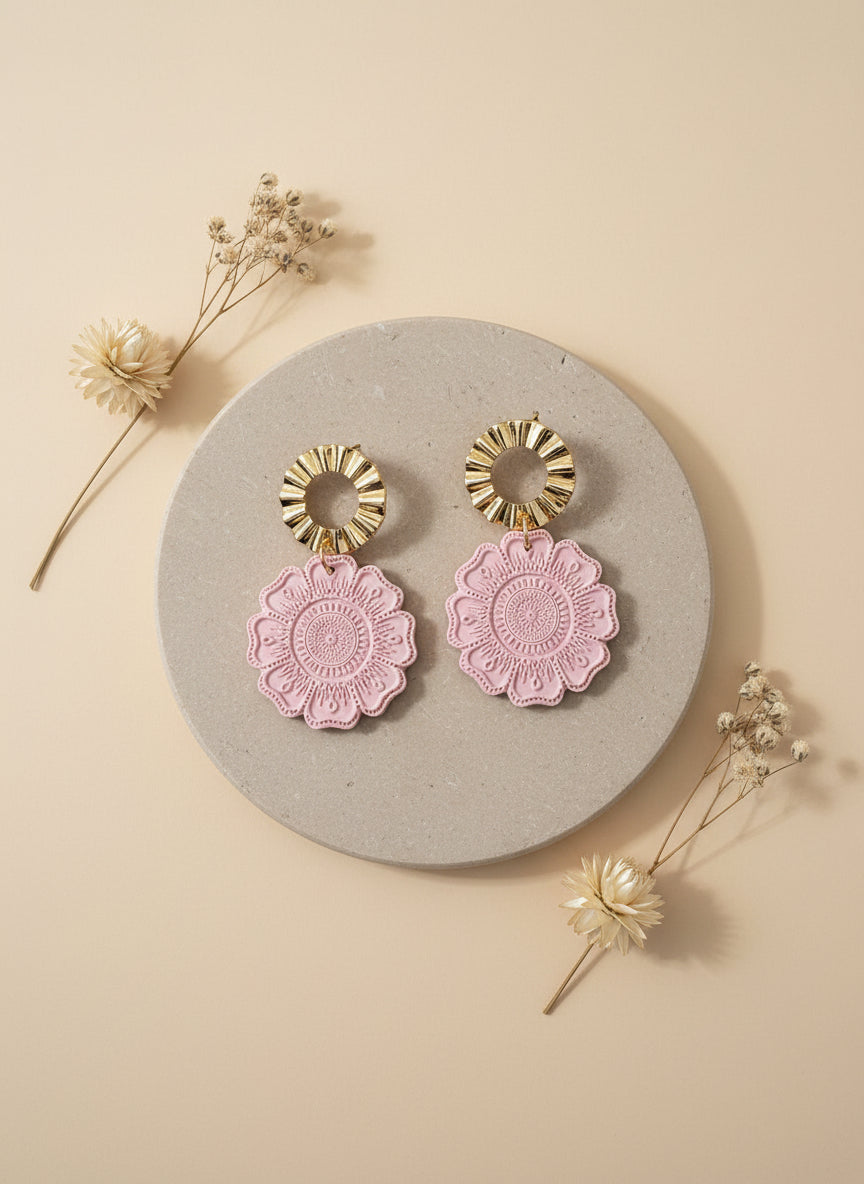 zachte perzik roze kleur oorbellen met een bloem textuur en gouden accenten
